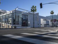 a view of a big modern building from a crosswalk near the intersection of two street