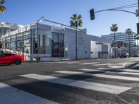 a view of a big modern building from a crosswalk near the intersection of two street