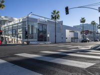 a view of a big modern building from a crosswalk near the intersection of two street