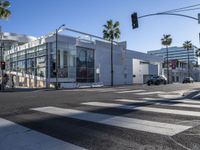 a view of a big modern building from a crosswalk near the intersection of two street