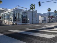 a view of a big modern building from a crosswalk near the intersection of two street