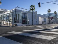 a view of a big modern building from a crosswalk near the intersection of two street