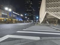 a modern building at night with traffic lights on the ground and street signs in front