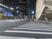 a modern building at night with traffic lights on the ground and street signs in front