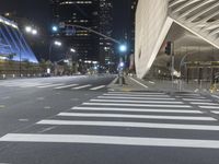 a modern building at night with traffic lights on the ground and street signs in front