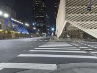 a modern building at night with traffic lights on the ground and street signs in front