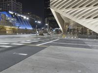 a modern building at night with traffic lights on the ground and street signs in front