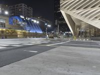 a modern building at night with traffic lights on the ground and street signs in front