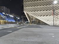 a modern building at night with traffic lights on the ground and street signs in front