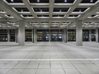 a long empty floor in a modern building with open air duct boxes and lights on the ceiling