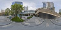 a fish eye photograph of a modern building at a park in the middle of a city