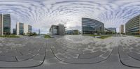 a small circular photo taken in the middle of a building plaza in europe looking at the large modern buildings