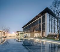 a very modern building near a pool in the evening light, reflecting off the glass pool