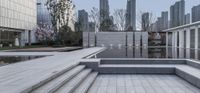 steps leading up to large square with fountain in outdoor courtyard of modern building site with trees on both sides