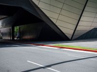 the curb is empty in front of the modern building, showing green and yellow lines