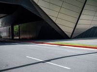 the curb is empty in front of the modern building, showing green and yellow lines