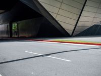 the curb is empty in front of the modern building, showing green and yellow lines