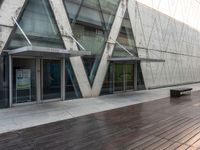 an empty wooden walkway outside a modern building with glass doors and railings on it