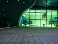 an illuminated, modern building with a green lighted entrance and windows on the side of it