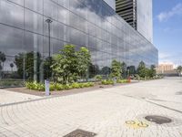 a very modern looking building with green plants in front of it and trees around it