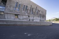 a person on a skate board rides a rail in front of a modern building in an industrial area