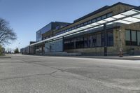 a building with a long glass canopy at the bottom of it is next to a street