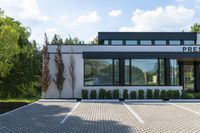 this is the front entrance to an office with windows and a brick walkway and bushes