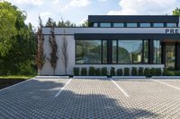 this is the front entrance to an office with windows and a brick walkway and bushes