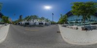 a fisheye lens shot of a park bench outside a building with an unusual tree and bench area