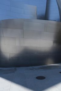 a fire hydrant sits near a very modern building wall on the corner of the walkway