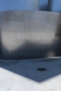 a fire hydrant sits near a very modern building wall on the corner of the walkway