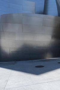 a fire hydrant sits near a very modern building wall on the corner of the walkway