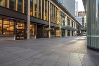 an empty sidewalk lined with modern buildings on either side of them, during the day