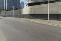 an empty street with modern buildings in the background and tall concrete blocks surrounding it, on a sunny day