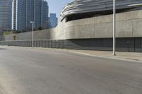 an empty street with modern buildings in the background and tall concrete blocks surrounding it, on a sunny day