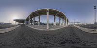 a bus station with arched roof and pillars, outside and in view a bus stop