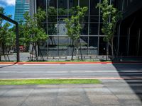 the bus stop sign is near a building with large windows and tree lined sidewalk in front of it