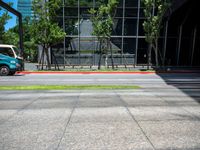 the bus stop sign is near a building with large windows and tree lined sidewalk in front of it