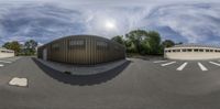 the reflection of a building with a parking lot on it, seen from a fish eye lens