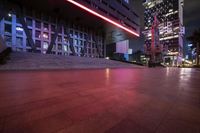 red lights in the middle of a city at night time, illuminating the building's outside