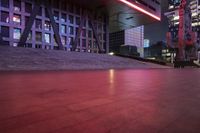 red lights in the middle of a city at night time, illuminating the building's outside