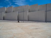 the gray concrete walls of a building have a line of steps on the left side