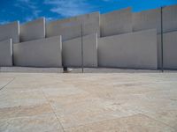 the gray concrete walls of a building have a line of steps on the left side