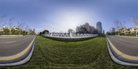 the view from a fish eye lens of a road near a fountain in a city