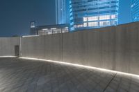 this is a photograph of an illuminated concrete wall, by the city at nighttime