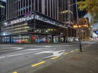 a very large glassy building with a arrow painted on the side of it at night