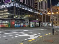 a very large glassy building with a arrow painted on the side of it at night