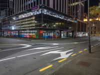 a very large glassy building with a arrow painted on the side of it at night