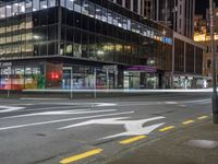 a very large glassy building with a arrow painted on the side of it at night