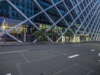 a long empty city street with some glass buildings in the background at night time and with many white lines on the ground